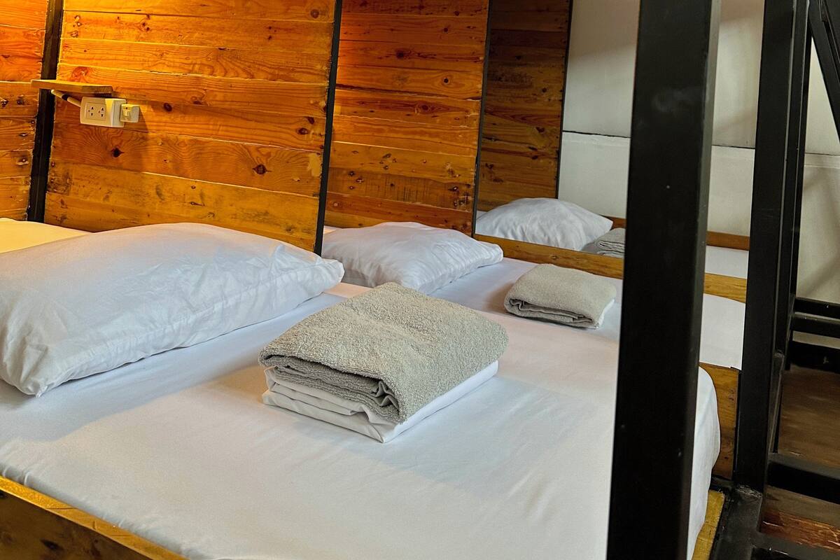 Ein holzgetäfeltes Zimmer im Blockhauskamin mit Etagenbetten, Holzbalkendecke und einer einzelnen Lampe.