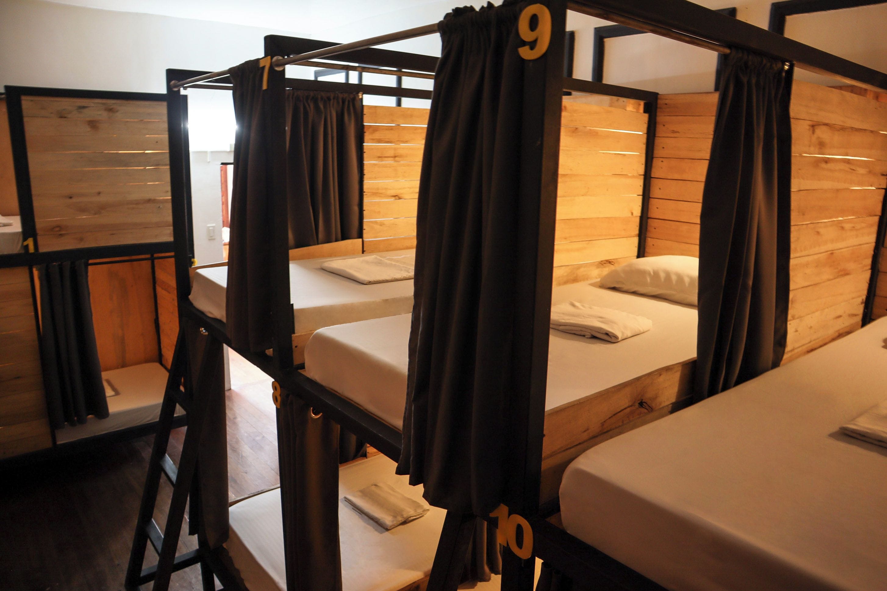 Un dormitorio con literas, paredes de madera y cortinas.
