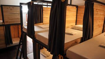 Un dormitorio con literas, paredes de madera y cortinas.