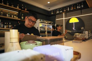 A bar area with shelves of bottles, a refrigerator, and a neon umbrella sign. - Yellow Umbrella (Cebu City)