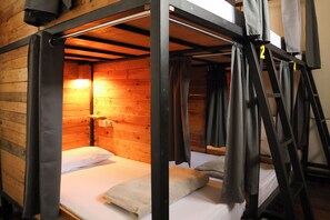 Habitación con literas, interior de madera, una mesita de noche y una lámpara.