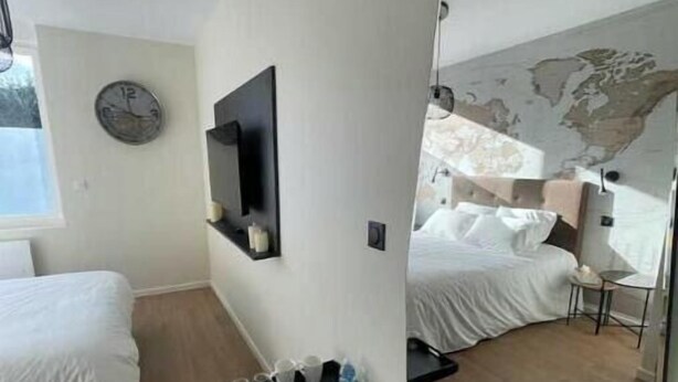 Een moderne hotelkamer met twee bedden, een flatscreen televisie, een wereldkaart muurschildering en een klein tafeltje met een waterfles.