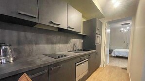 Een moderne keuken met donkere kastjes, een aanrecht en een zichtbare waterkoker.