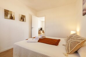 Une chambre à coucher avec un lit, un miroir, une télévision, une lampe et des œuvres d’art accrochées au mur.
