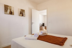 Une chambre à coucher avec un lit, un plaid marron et deux tableaux accrochés au mur.