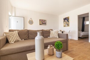 Un salon moderne avec un canapé, une table basse, un vase et une plante en pot.