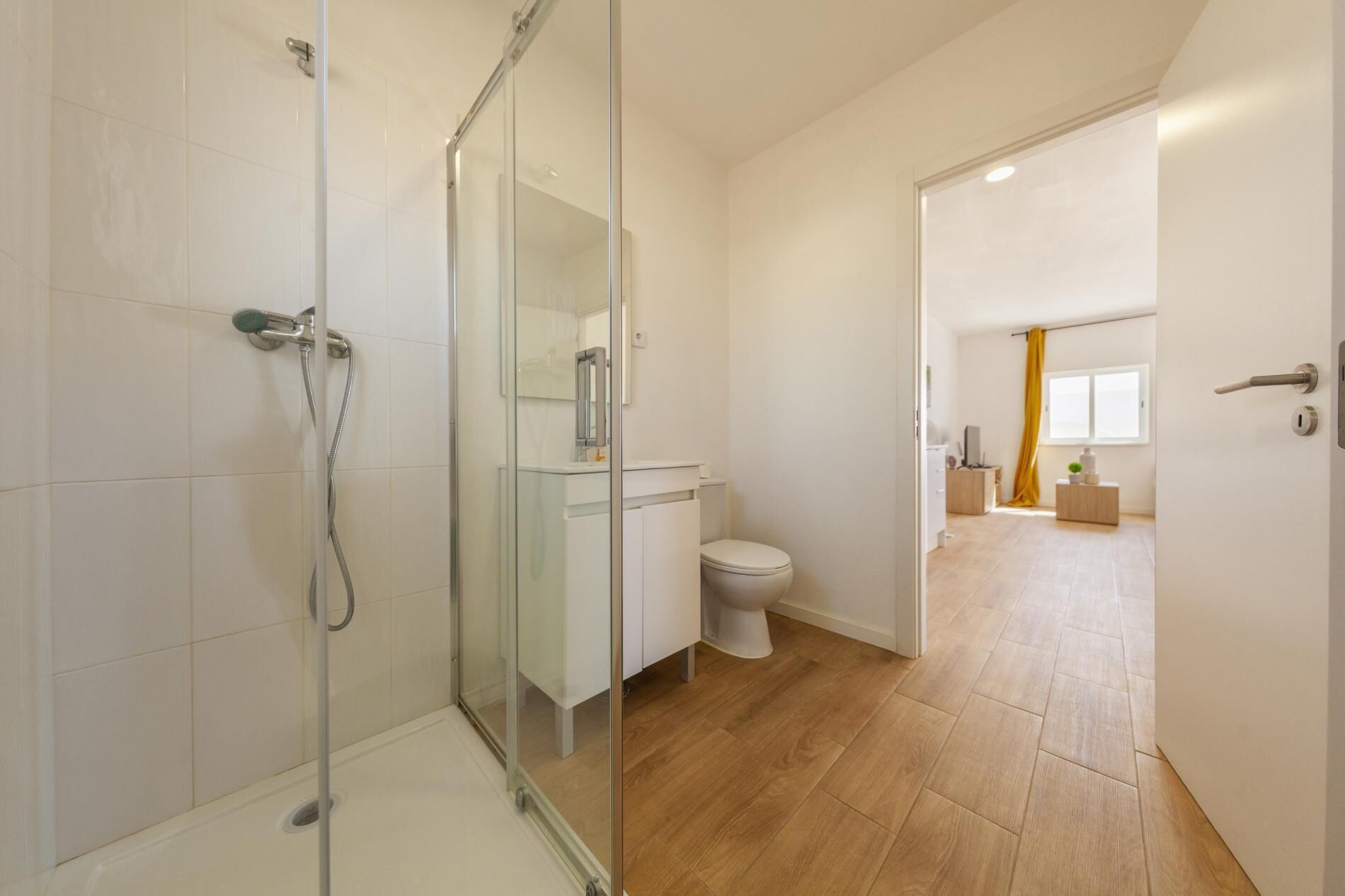 A modern bathroom with a glass shower enclosure, a toilet, and a sink.