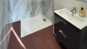 A modern bathroom with a glass-enclosed shower, a marble-tiled wall, a white sink, and a dark cabinet. - Suite "Art Déco" - 2/4 Pers (Niergnies)