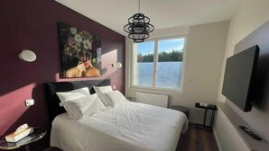 A bedroom with a bed, a TV, a window, and a painting on the wall. - Suite "Art Déco" - 2/4 Pers (Niergnies)