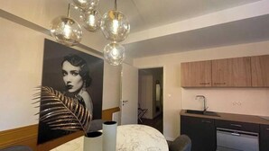 A modern kitchen with wooden cabinets, a built-in oven, and a marble dining table with two white vases. - Suite "Art Déco" - 2/4 Pers (Niergnies)