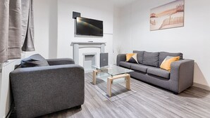 Un salon moderne avec un canapé, une table basse en verre, une cheminée et un téléviseur à écran plat fixé au-dessus de la cheminée.