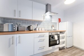 Eine moderne Küche mit weißen Schränken, einem Backofen, einer Mikrowelle und einem Wasserkocher.