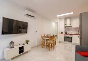 A modern kitchen with white cabinets, a built-in oven, and a dining area with a white table and chairs. - Vacation Apartment 'Rayito De Sol 2' with Shared Pool, Wi-Fi and Air Conditioning (San Bartolomé de Tirajana)