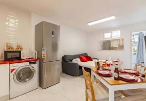Eine kompakte Küche mit Waschmaschine, Kühlschrank, Mikrowelle und Essbereich mit Tisch für zwei Personen.
