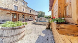 A stone building with a wooden porch and outdoor seating area. - A cosy farmhouse surrounded by nature! (Marche)