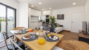 Un apartamento moderno con comedor, kitchenette y sala de estar con sofá y televisor.