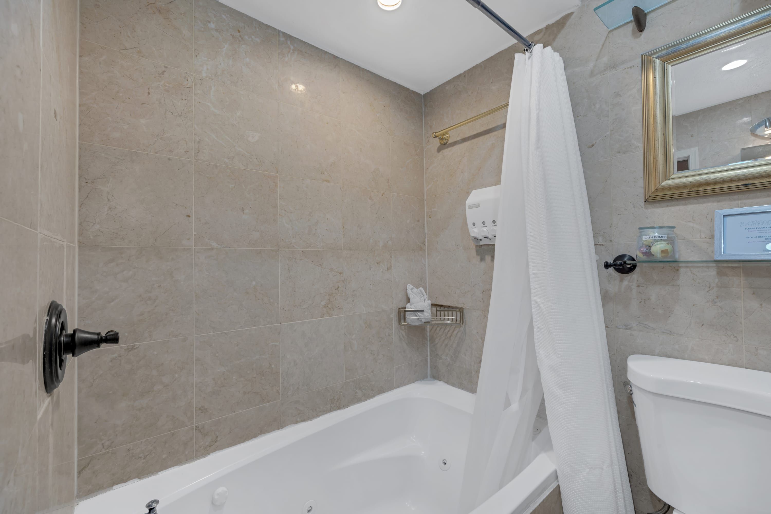 A bathroom with a bathtub, toilet, and a shower curtain.