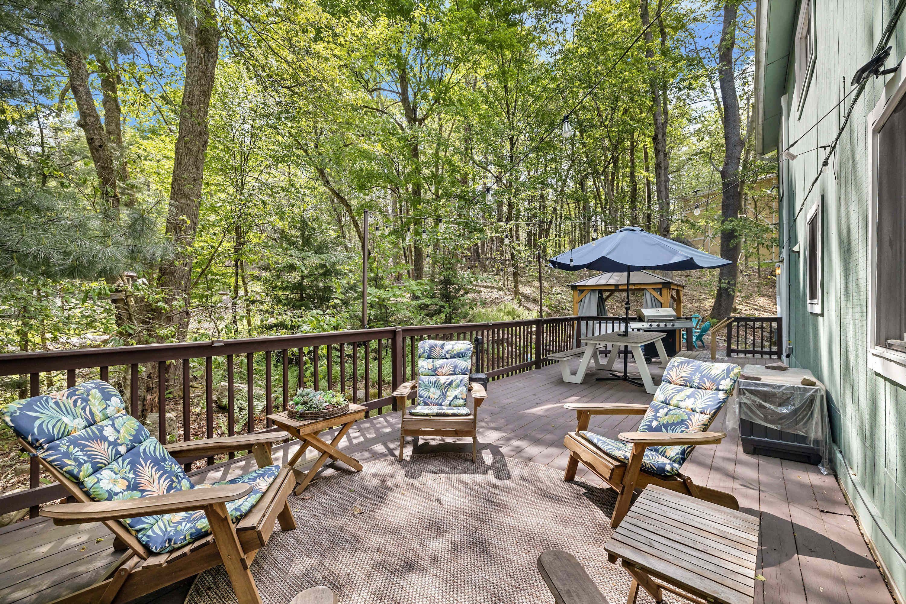 A wooden deck with outdoor furniture, a gazebo, and a view of a forested area.