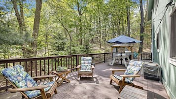 A wooden deck with outdoor furniture, a gazebo, and a view of a forested area.