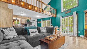 A modern living room with a grey sectional sofa, wooden coffee table, and a staircase leading to an upper level. - Cozy Poconos Retreat Hot Tub Dog Friendly Firepit (Pocono Lake)