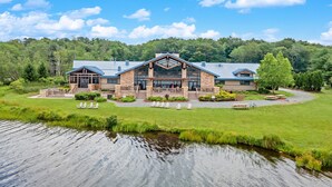 A lodge with a large central building, a covered outdoor seating area, and a small pond in the foreground. - Cozy Poconos Retreat Hot Tub Dog Friendly Firepit (Pocono Lake)