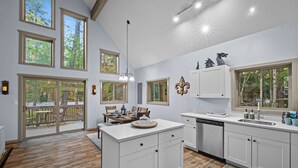 A spacious kitchen with large windows, a dining area with a table and chairs, and a view of the outdoors. - Near Jfbb for Skiing With Hot Tub and Fire Pit (Blakeslee)