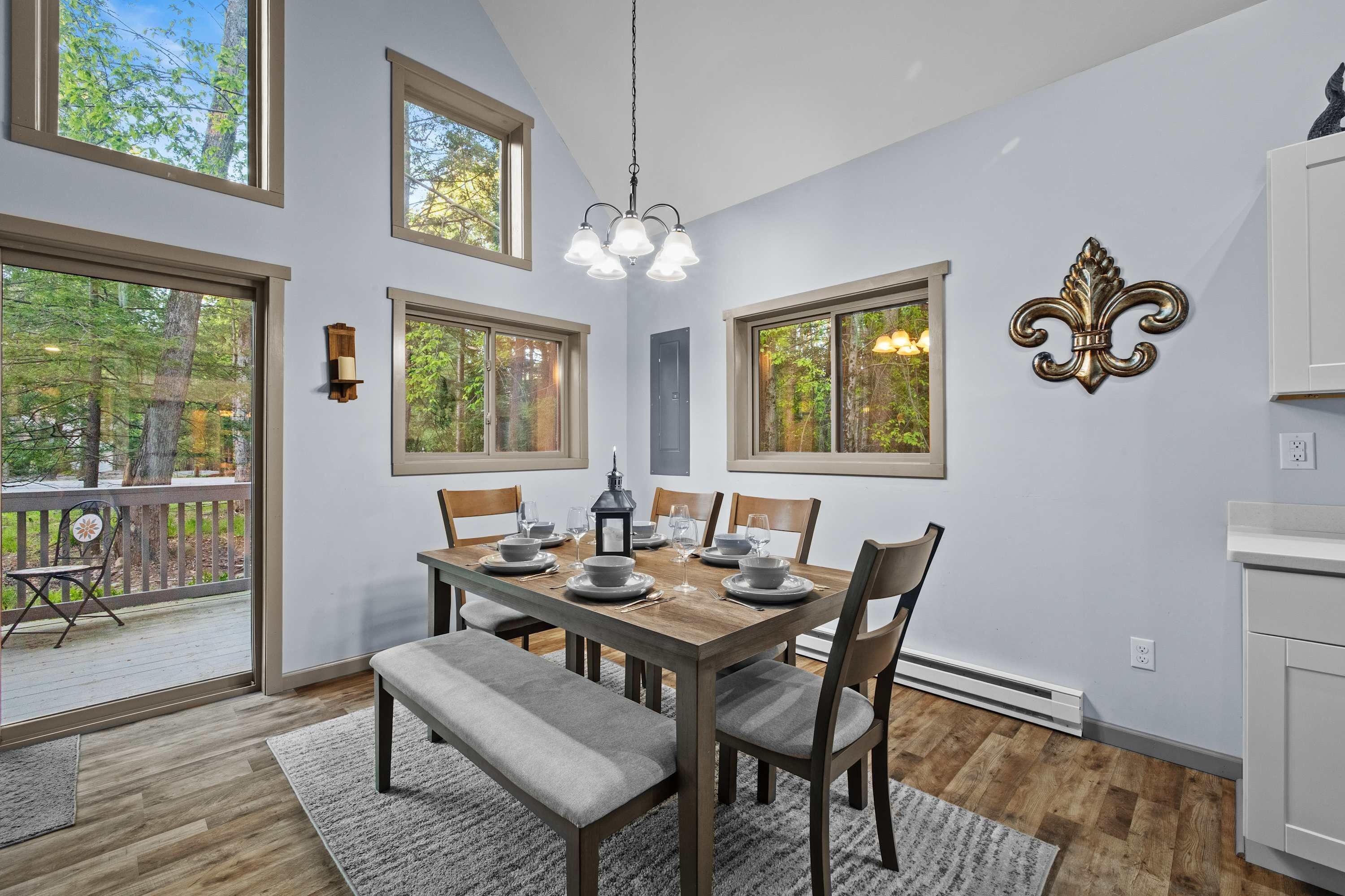 A dining room with a wooden table, chairs, a bench, and a chandelier.