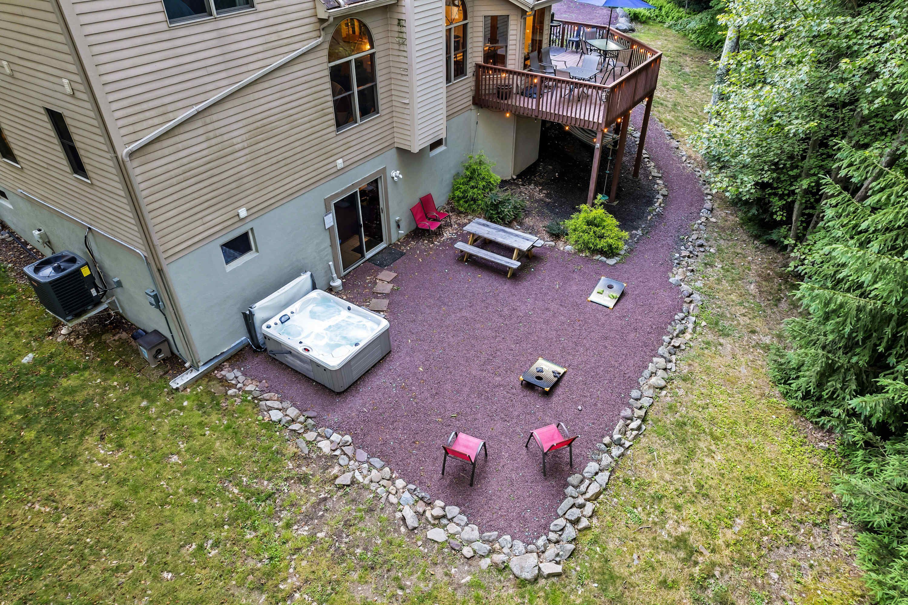 A backyard with a hot tub, a deck, and outdoor seating.