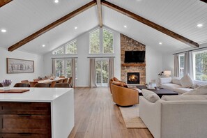 A spacious living area with a high ceiling, a stone fireplace, and large windows. - Hottub Firepit Gameroom 10mins2jackfrostbigboulder (Blakeslee)