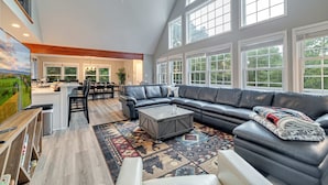 A spacious living room with a large sectional sofa, a coffee table, and a dining area with chairs and a table. - Hot Tub Game Room Dog Friendly Sports Bar A C (Albrightsville)