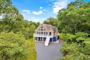 Une maison à deux étages dotée d’un balcon, entourée d’une végétation luxuriante.