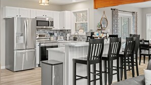 A modern kitchen with stainless steel appliances, a white island, and black bar stools. - Hot Tub Game Room Dog Friendly Sports Bar A C (Albrightsville)