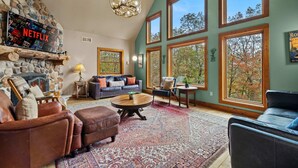 A cozy living room with a stone fireplace, leather sofas, a large window, and a Netflix sign. - Fam-friendly Cabin Mins 2 Beach Ski w Hot Tub (Lake Harmony)