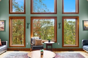 A room with large windows, a sofa, a chair, a small table, and a rug. - Fam-friendly Cabin Mins 2 Beach Ski w Hot Tub (Lake Harmony)
