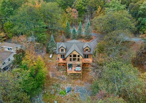 A cabin with a central deck, surrounded by dense forest. - Fam-friendly Cabin Mins 2 Beach Ski w Hot Tub (Lake Harmony)