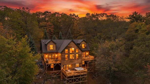A two-story wooden cabin with a balcony, surrounded by forest. - Fam-friendly Cabin Mins 2 Beach Ski w Hot Tub (Lake Harmony)