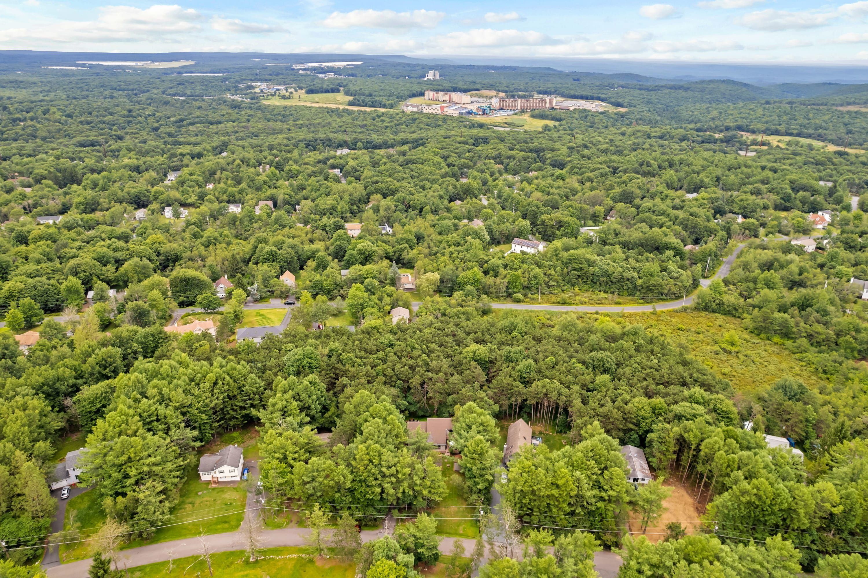 An aerial view of a residential area with houses, roads, and a large building in the distance.