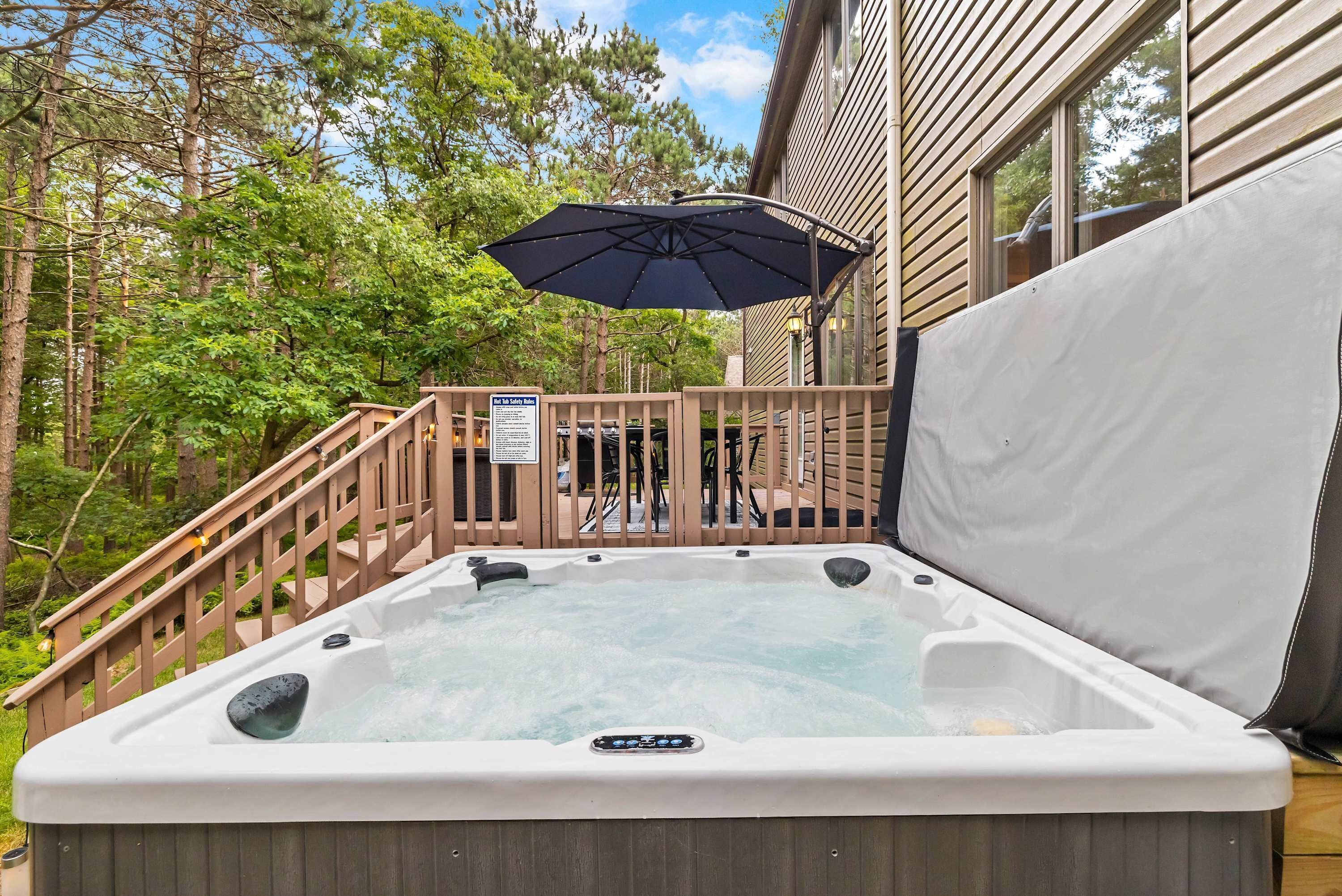 A hot tub with a wooden deck and a covered area, surrounded by trees.
