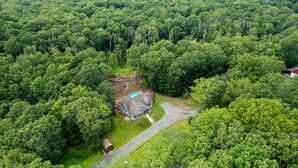 Et hus omgivet af tæt skov, med en indkørsel til indgangen.