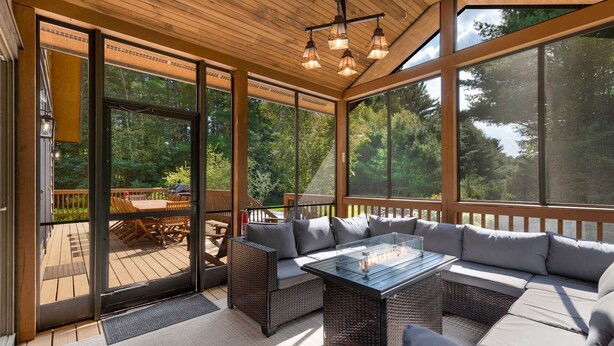 A covered patio area with wicker furniture, large windows, and a ceiling light fixture. - Whiteface Views Hot Tub Game Room Dog Friendly (Wilmington)