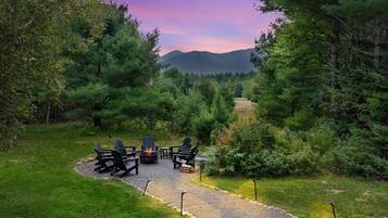 A gravel path leading to a fire pit area with Adirondack chairs.