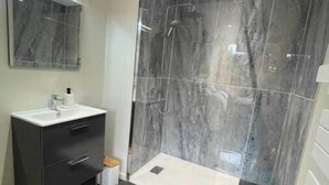 A modern bathroom with a marble shower, a sink with a mirror, and a small trash bin. - Suite "Petit Prince" - 2/4 Pers (Niergnies)