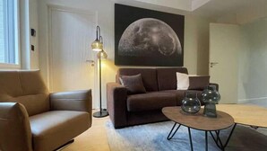 A modern living room with a sofa, a coffee table, and a floor lamp. - Suite "Petit Prince" - 2/4 Pers (Niergnies)