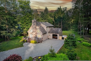 A house with a stone chimney, a garage, and a well-maintained garden. - Near Jfbb With Private Hot Tub and Game Room (Albrightsville)