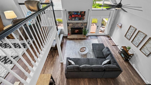 A modern living room with a fireplace, a sofa, a coffee table, and a TV mounted above the fireplace. - Near Jfbb With Private Hot Tub and Game Room (Albrightsville)