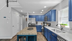 A modern kitchen with blue cabinets, a stainless steel refrigerator, and a wooden island. - Near Jfbb With Private Hot Tub and Game Room (Albrightsville)