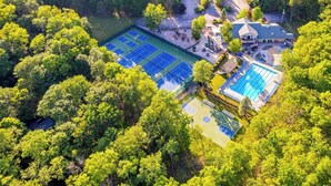 An aerial view of a property with multiple tennis courts surrounded by dense greenery. - Lakefront Poconos Retreat w Hot Tub Dog Friendly (Gouldsboro)