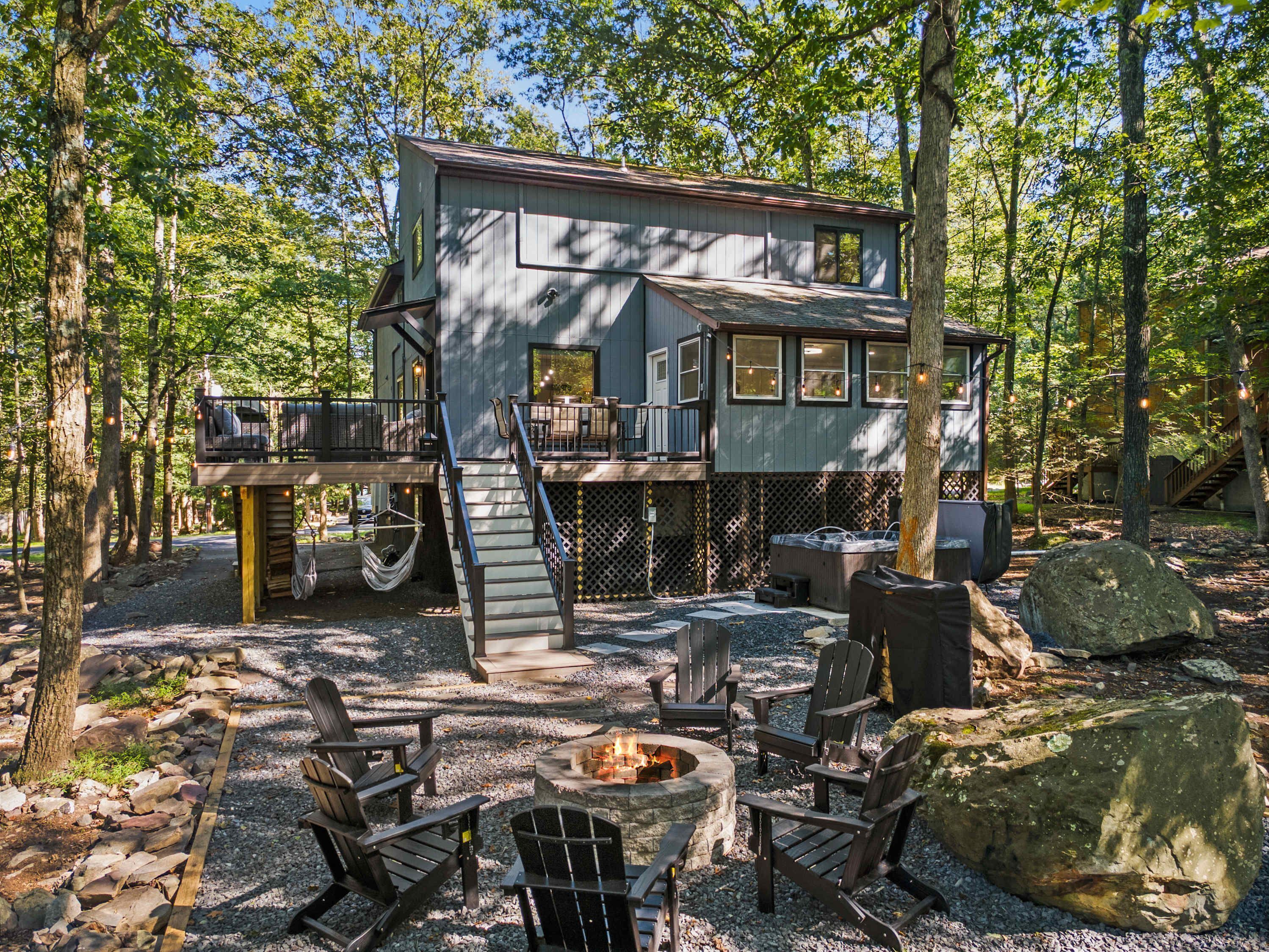 A cabin with a deck, a fire pit, and outdoor seating.