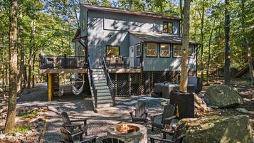 A cabin with a deck, a fire pit, and outdoor seating.