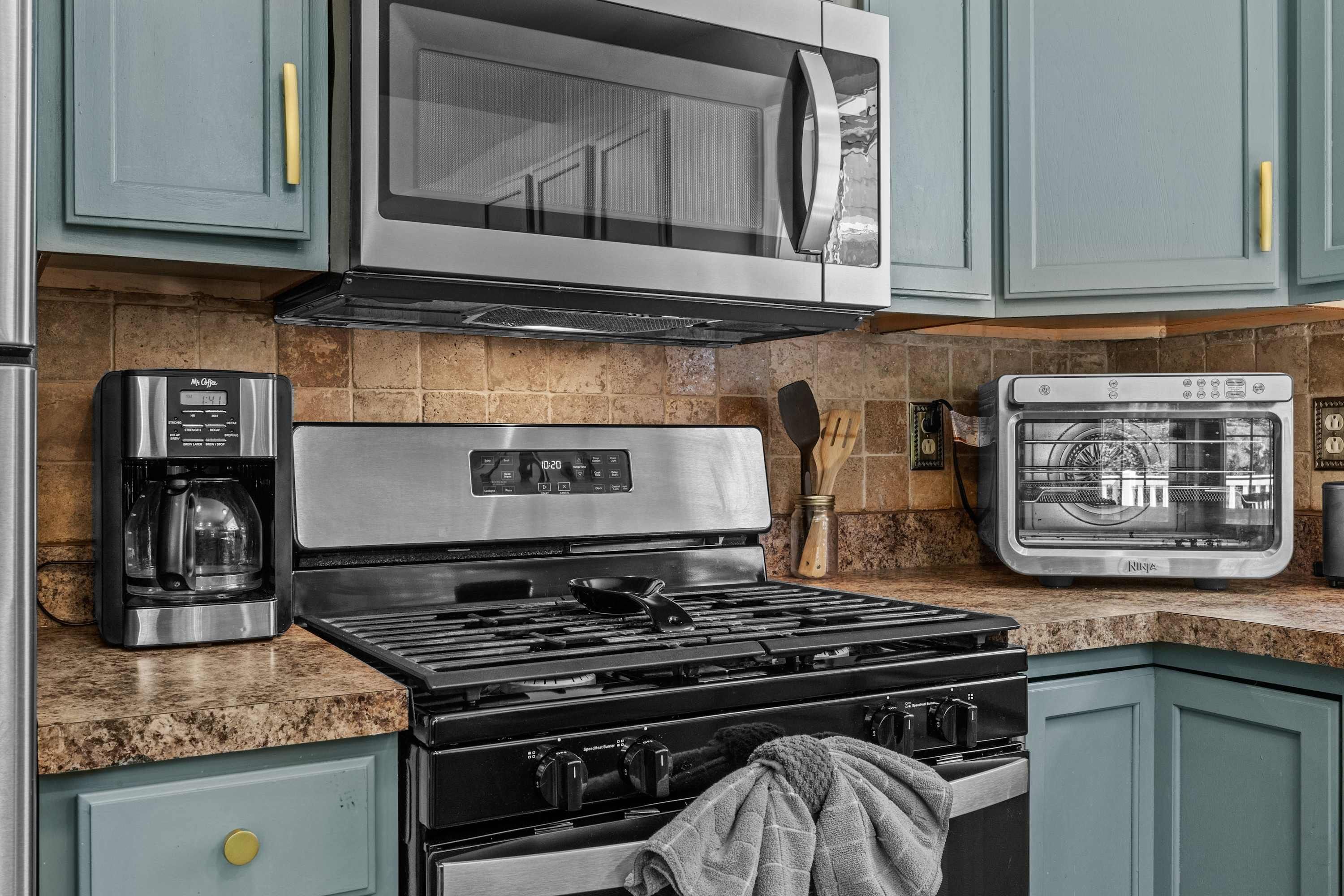 Une cuisine équipée d’une cuisinière en acier inoxydable, d’un four à micro-ondes, d’une machine à café et d’un four traditionnel.